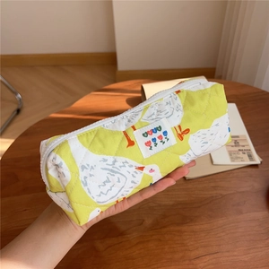 Detailed macro of yellow quilted fabric pencil case featuring cute white duck patterns
