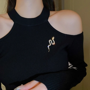 Detail of a gold snake brooch with white zircons pinned on a black knitted sweater