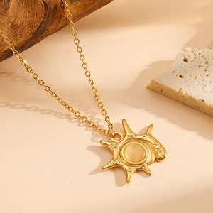 Detail of 18K gold-plated sun pendant necklace with yellow gemstone on stone
