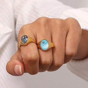 Detail of 18K gold-plated signet rings with abalone shell and blue inlay on model hand