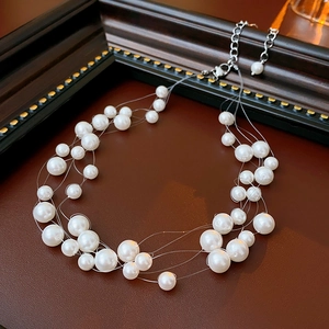 Detail of multi-layer pearl necklace with white faux pearls on invisible fishing line