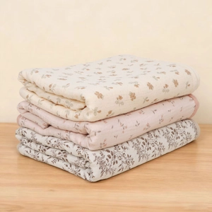 Detailed view of three soft cotton muslin swaddle blankets with floral and leaf patterns