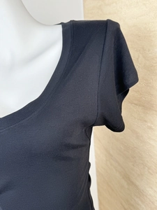 Macro detail of the fine wool blend knit texture and V-neck stitching on the black top