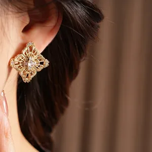 Retro hollow flower stud earrings in gold with zircon accents worn by a model