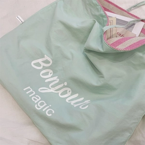 Détail du sac cabas en toile vert menthe avec imprimé Bonjour et anses rayées