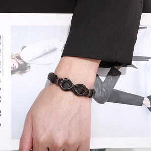 Men's braided leather bracelet with black infinity symbol clasp on a wrist