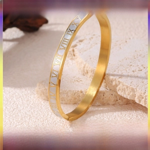 Detail of gold and silver stainless steel bangle featuring engraved Roman numerals I-XII