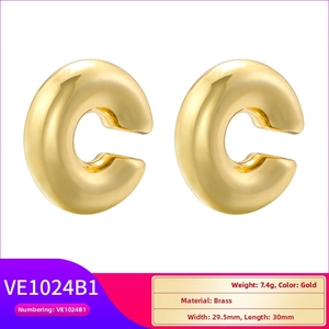 Macro detail of gold C-shape earrings showing size, weight, and brass material specifications
