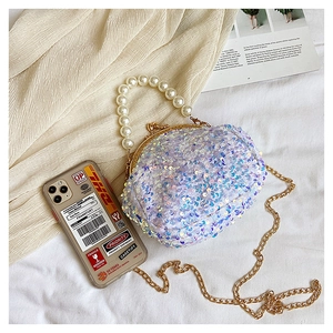 Detail of sequined round shell bag featuring pearl handle and golden chain strap