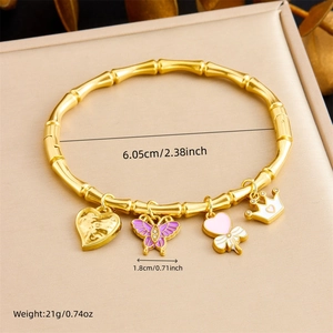 Detail of a gold bamboo-textured bangle with heart, butterfly, clover and crown charms