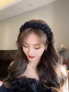 Elegant pleated black mesh headband with oversized floral design on a model