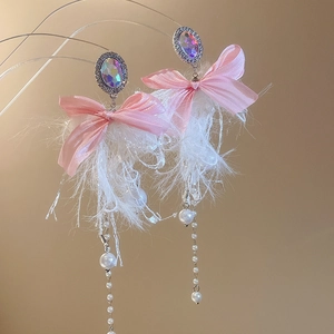 Detail of pink bow earrings with white feathers, crystal inlay and pearl tassel accents