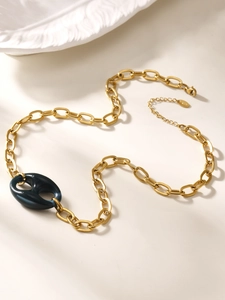 Detailopname van gouden grove ketting met een donkerblauwe hars ovale schakel