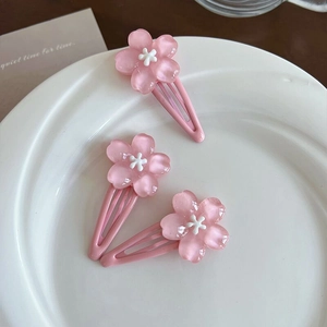 Detailed view of three pink cherry blossom resin hair clips on a white ceramic plate