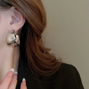 Détail de la boucle d'oreille en C argentée avec textures lisse et martelée mélangées
