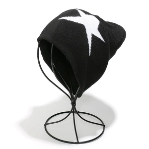 Détail du bonnet en maille noire avec un motif d'étoile blanche sur fond blanc pur