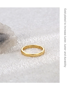 Detail view of 18K gold plated ring with three zircons on white textured background