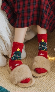 Detailed close-up of thick red Christmas socks with embroidered trees and warm fleece texture