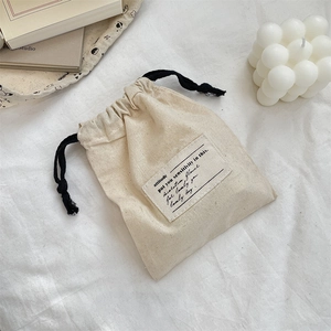 Close-up of beige cotton drawstring pouch with lovely day label and bubble candle