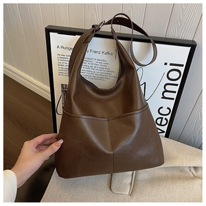 Détail d'un sac cabas en cuir marron foncé montrant une texture et un design épuré