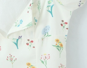 Detail des Blumenkleids mit Erdbeerdruck und Spitzennähten an der Taille