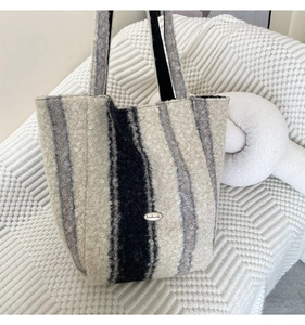 Detail of wool-like texture on a striped tote bag with a handmade tag on a sofa