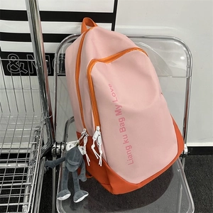 Close-up of pink and orange nylon backpack showing side pocket and cute frog charm accessory