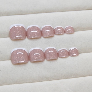 Faux ongles d'orteils blancs style french sur base rose nude et paillettes argent