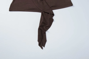 Dettaglio dell'orlo superiore in maglia marrone scuro con lacci decorativi e cuciture pulite
