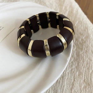 Macro view of wide elastic bracelet with dark brown acrylic and gold polished metal links