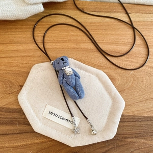 Détail du collier ourson en denim bleu avec décorations de cristal et perle de luxe