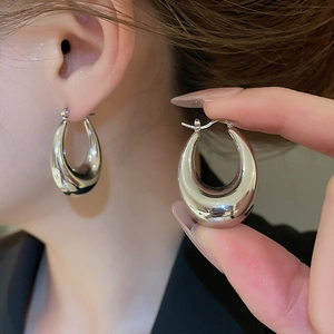 Macro detail of chunky silver C-shape hoop earrings with high-polish mirror finish