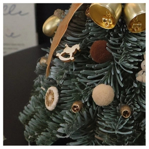 Detailed view of handmade mini Christmas tree with golden bell and wooden rocking horse