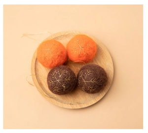 Close-up of wool felt Christmas balls with gold snowflake embroidery in a wooden tray