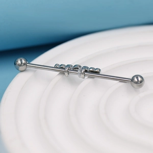 Gros plan d'un piercing industriel argenté avec cristal marquise sur support blanc