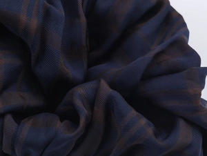 Close-up of high-quality dark blue and brown plaid twill fabric texture with soft folds