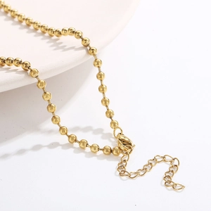Dettaglio collana a sfere dorate con chiusura a moschettone sicura e catena di estensione
