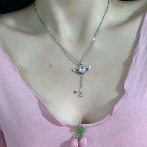 Détail du collier coeur ailé avec pierre violette et pompon porté par un mannequin
