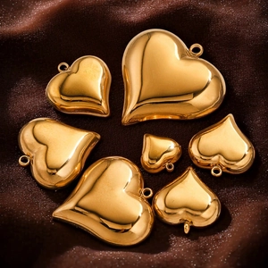 Polished gold stainless steel heart charms in various sizes on brown velvet