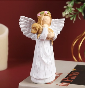 Close-up of white resin angel statue with flower crown holding a brown dog on a red wall