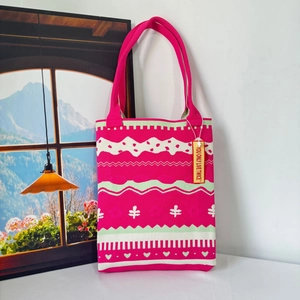 Detail of fuchsia knit tote bag featuring green geometric patterns and woven texture