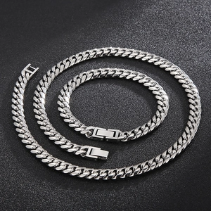 Close-up of silver-tone polished Cuban link chain set on textured black background