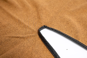 Close-up of textured brown fabric shawl with elegant black leather-like trim detail