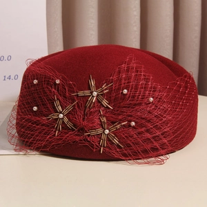Detail of burgundy wool beret featuring elegant mesh bow and star beadwork accents