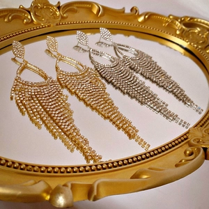 Luxury rhinestone tassel earrings in gold and silver finish on a golden mirror tray