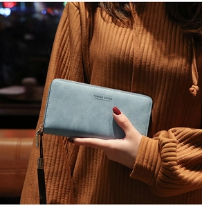 Detail of light blue textured PU leather long wallet with wristlet held by a model