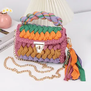 Detail view of colorful handmade crochet bag with gold lock, chain and textile fringe
