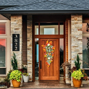 Fall harvest door wreath with white pumpkins and maple leaves on a wooden front door
