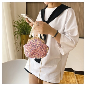 Macro detail of pink sequin shell bag with large pearl handle and metal clasp