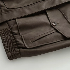 Detail of dark brown PU jacket featuring flap pockets and elastic ribbed hemline